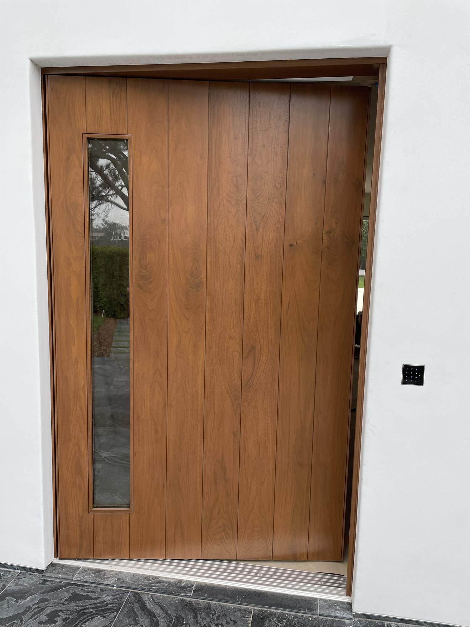 Hand-brushed forest-green front door with satin-brass hardware and matching sidelights