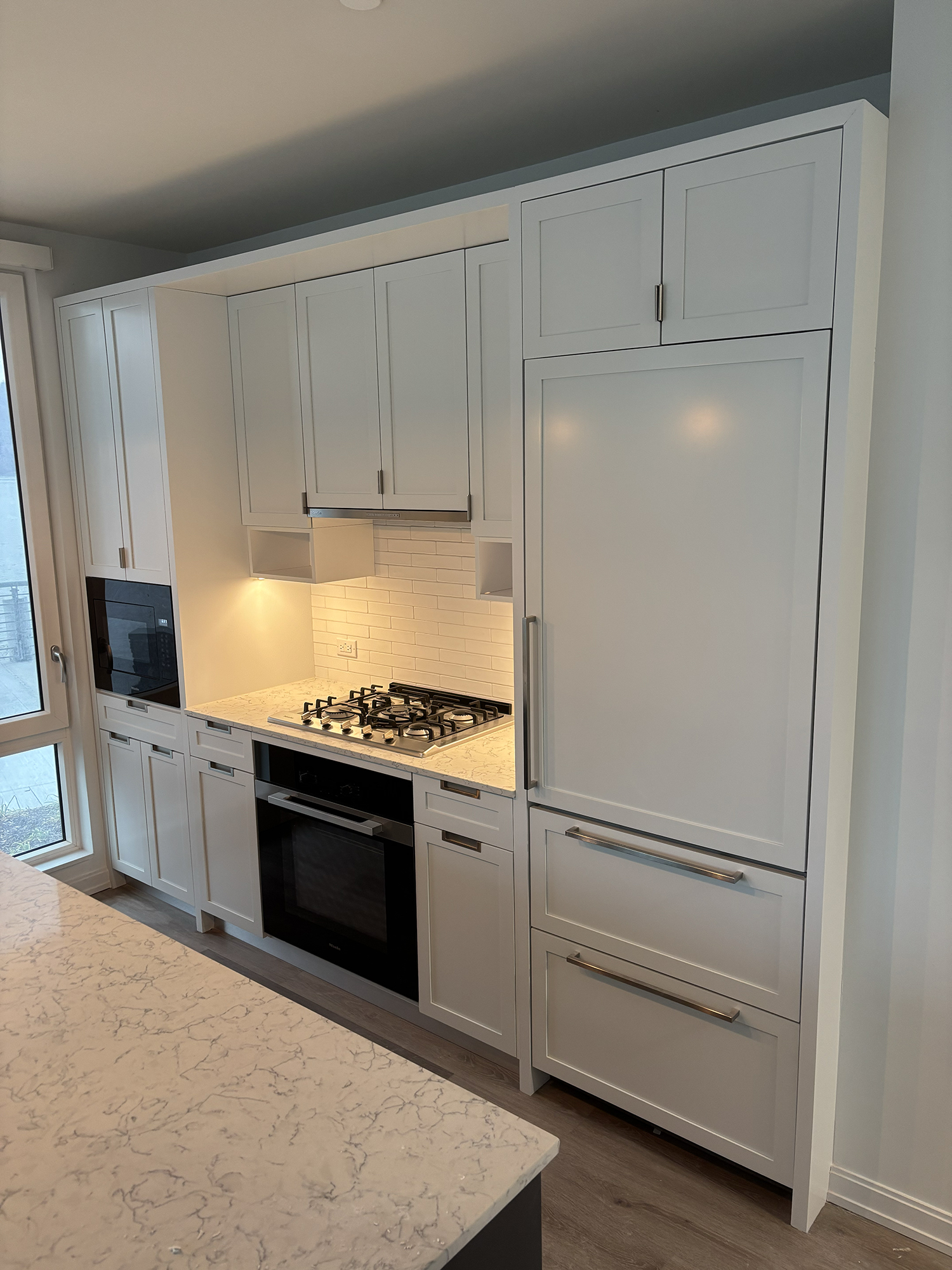 Kitchen island and cabinets refinished in a two-tone color scheme with brushed brass hardware